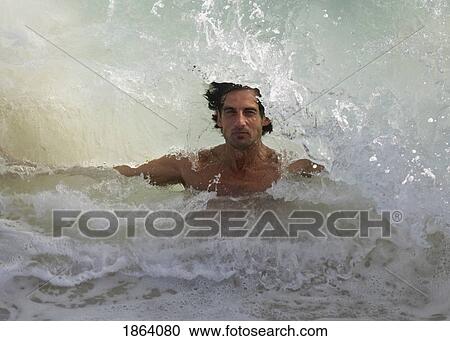 Stock Image - Wave Splashing Over Man. Fotosearch
