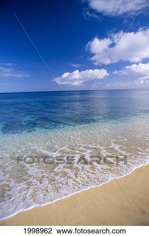 Stock Image - Wave Washes Ashore Onto Sandy Beach, Azure Ocean, Blue Sky B1498. Fotosearch