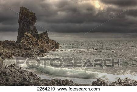 Waves crash over the rocky beach of djupalonssandur by a coastal volcanic plug; iceland View Large Photo Image Stock Image - Waves crash over the rocky beach of djupalonssandur by a coastal volcanic plug; iceland. Fotosearch