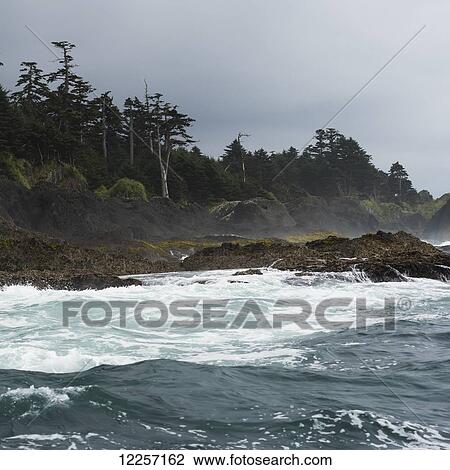 Stock Image - Waves crashing along the coast under dark clouds; Skeena-Queen Charlotte, British Columbia, Canada. Fotosearch