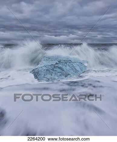 Stock Image - Waves from the atlantic ocean crash into ice calf from breioamerkurjokull a glacial tongue of the vatnajokull ice cap; iceland. Fotosearch