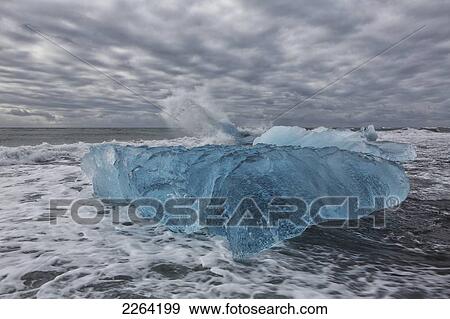 Stock Photo - Waves from the atlantic ocean crash into ice calf from breioamerkurjokull a glacial tongue of the vatnajokull ice cap; iceland. Fotosearch