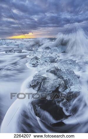 Stock Photo - Waves from the atlantic ocean crash into ice calf from breioamerkurjokull a glacial tongue of the vatnajokull ice cap; iceland. Fotosearch