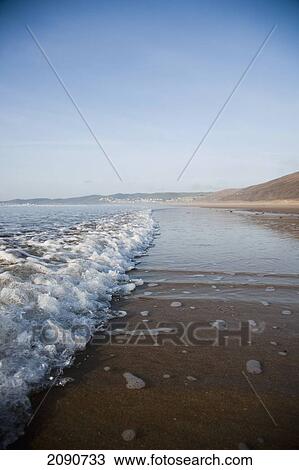 Waves Lapping On The Sandy Beach, On A Calm Sunny Day At Putsborough Sands, North Devon, Uk View Large Photo Image Stock Image - Waves Lapping On The Sandy Beach, On A Calm Sunny Day At Putsborough Sands, North Devon, Uk. Fotosearch