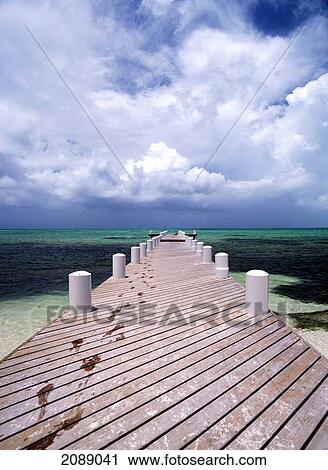 Stock Image - Wet Footprints Leading Up A Wooden Pier From The Ocean. Fotosearch
