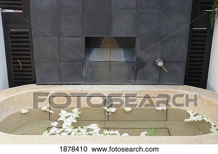 Stock Image - White Flowers Floating In Marble Bathtub. Fotosearch
