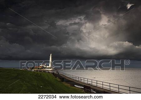 Picture - White Lighthouse Illuminated By Sunlight Under Dark Storm Clouds; St. Mary's Island Northumberland England. Fotosearch