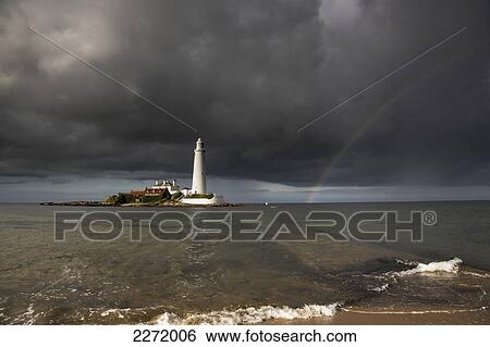 White Lighthouse Illuminated By Sunlight Under A Dark Stormy Sky With A Rainbow; St. Mary's Island Northumberland England View Large Photo Image Stock Photograph - White Lighthouse Illuminated By Sunlight Under A Dark Stormy Sky With A Rainbow; St. Mary's Island Northumberland England. Fotosearch