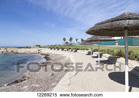 Stock Photography - White sand beach with umbrellas lining the coast; Yeroskipou, Paphos, Cyprus. Fotosearch