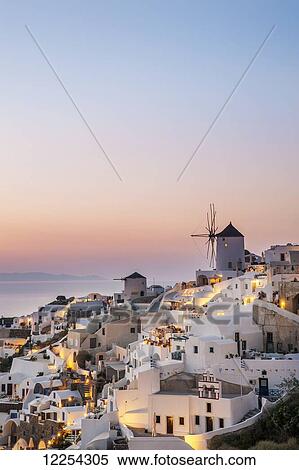 Stock Photography - Whitewash buildings and windmill at dusk; Oia, Santorini, Greece. Fotosearch