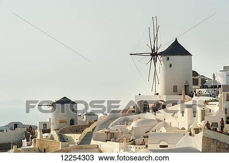 Stock Image - Whitewash buildings and windmill; Oia, Santorini, Greece. Fotosearch