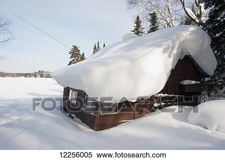 Stock Photography - Wilderness camp covered in snow in winter near a frozen lake; Ontario, Canada. Fotosearch