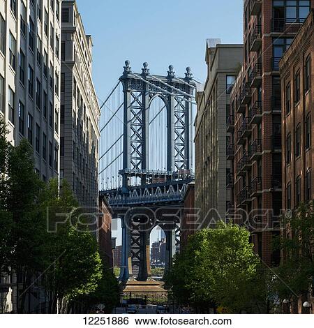 Stock Photograph - Williamsburg bridge and buildings against a blue sky; New York City, New York, United States of America. Fotosearch