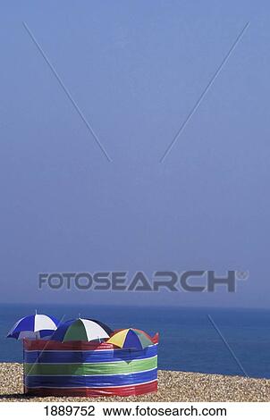Stock Image - Windbreaker And Umbrellas On Pebble Beach. Fotosearch