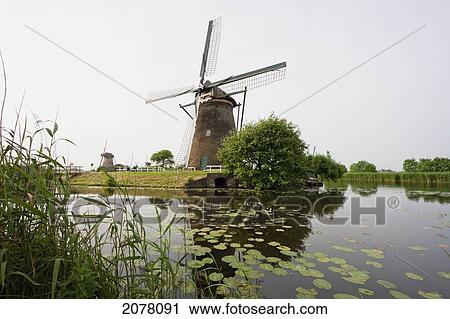 Windmill, Built Around 1740 To Drain The Excess Water From The Alblasserwaard Polders, Reflected In Nieuwe Waterschap, Kinderdijk, Netherlands View Large Photo Image Stock Image - Windmill, Built Around 1740 To Drain The Excess Water From The Alblasserwaard Polders, Reflected In Nieuwe Waterschap, Kinderdijk, Netherlands. Fotosearch