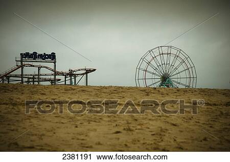 Stock Image - Winter on a deserted beach with a closed funfair in the background; Skegness, Lincolnshire, England. Fotosearch