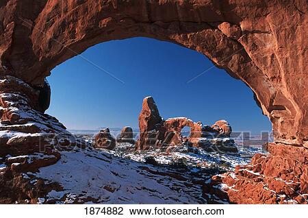 Stock Image - Winter Snow Covers Turret Arch Looking Through The North Window Formation At Arches National Park; Utah, Usa. Fotosearch