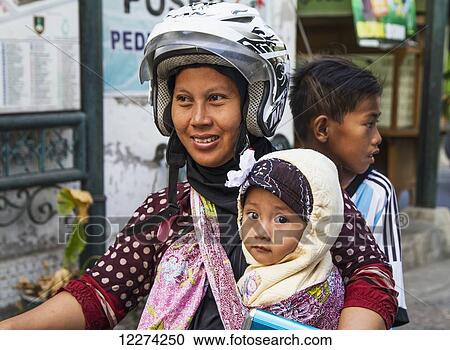Stock Image - Woman and children on a motorcycle, Kampung Kauman, Surakarta (Solo), Central Java, Indonesia. Fotosearch