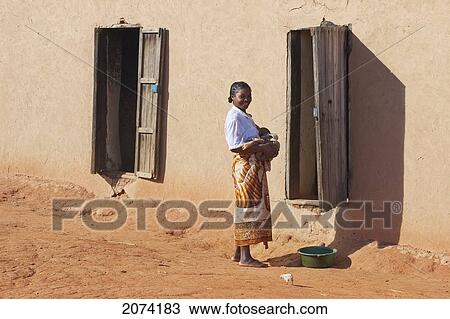 Stock Image - Woman By Her House In A Merina Village Along The Road Between Ambositra & Ambavalao, Fianarantsoa Province, Madagascar. Fotosearch