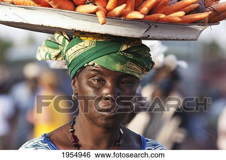 Stock Photograph - Woman carrying carrots of her head in Mopti, Mali. Fotosearch