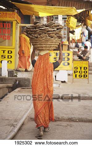 Stock Image - Woman Carrying Cow Dung In Basket On Head, Om Kareshwar, Madhya Pradesh, India. Fotosearch