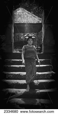 Stock Image - Woman Carrying Plate With Hot Food On Head; Ubud, Bali, Indonesia. Fotosearch