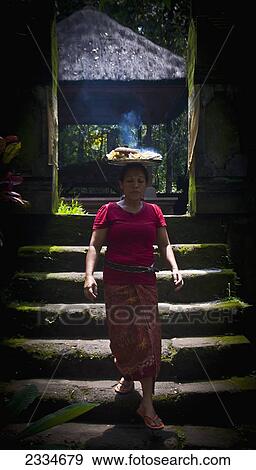 Stock Photo - Woman Carrying Plate With Hot Food On Head; Ubud, Bali, Indonesia. Fotosearch