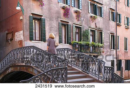 Woman crossing a bridge over a canal; Venice, Italy View Large Photo Image Stock Photo - Woman crossing a bridge over a canal; Venice, Italy. Fotosearch