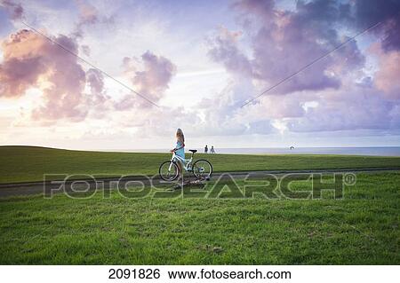 Stock Photograph - Woman Cycling Through The Coastal Makai Golf Course; Princeville, Kauai, Hawaii. Fotosearch