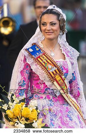 Stock Photo - Woman Dressed Up In Traditional Casal Faller Dress In Procession With Flower Offering For Virgin De Los Desamparados At Fallas Festival; Valencia, Spain. Fotosearch