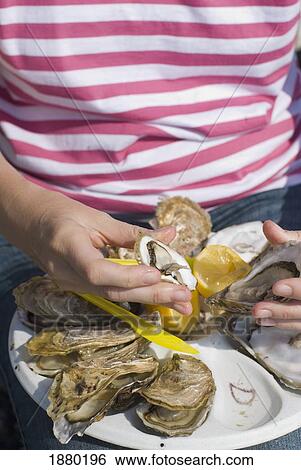 Stock Photograph - Woman Eating Oysters In Cancale, Close Up. Fotosearch