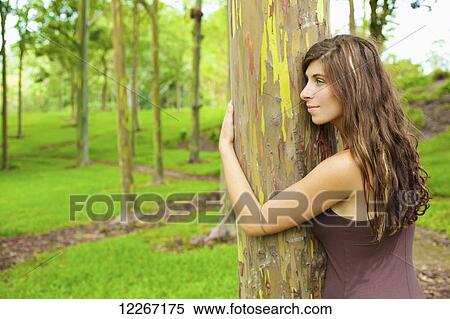 Stock Photography - Woman embracing a tree trunk; Kauai, Hawaii, United States of America. Fotosearch