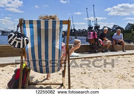 Woman enjoying the summer sun on the man-made beach at Royal Victoria Dock; London, England View Large Photo Image Stock Image - Woman enjoying the summer sun on the man-made beach at Royal Victoria Dock; London, England. Fotosearch