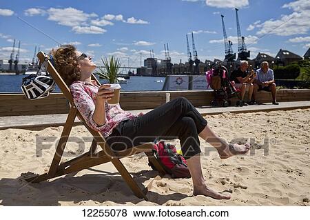 Woman enjoying the summer sun on the man-made beach at Royal Victoria Dock; London, England View Large Photo Image Stock Photo - Woman enjoying the summer sun on the man-made beach at Royal Victoria Dock; London, England. Fotosearch