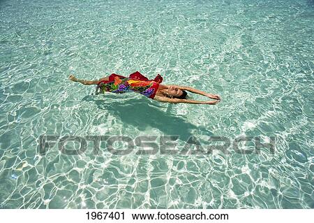 Stock Image - Woman Floating In Tropical Ocean Water.. Fotosearch