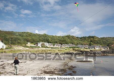 Stock Photography - Woman Flying A Kite On Beach, Island Of Arran, Scotland. Fotosearch