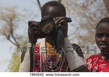 Stock Image - Woman From Shompole Maasai Tribe Looking Through A Camera, Kenya, Africa. Fotosearch