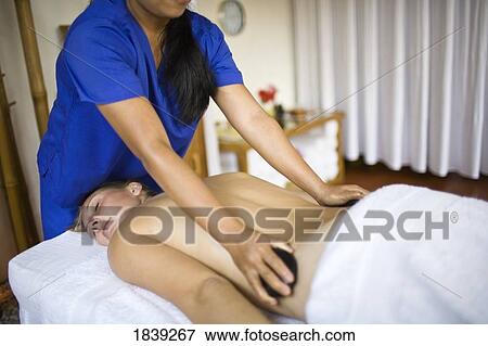 Woman Getting Hot Stone Massage By Masseuse; Puerto Gallera, Mindoro Island, Philippines View Large Photo Image Stock Photo - Woman Getting Hot Stone Massage By Masseuse; Puerto Gallera, Mindoro Island, Philippines. Fotosearch