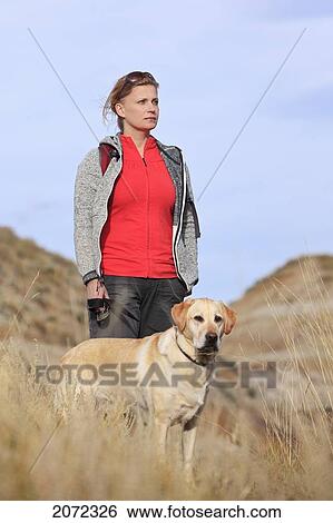 Stock Photograph - Woman Hiking With Her Yellow Labrador Retriever In The Badlands Of Drumheller, Alberta, Canada. Fotosearch