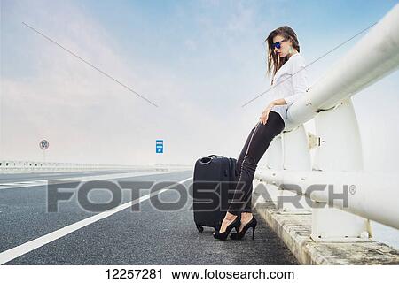 Woman hitchhiking on a highway, resting on a railing with her luggage; Xiamen, Fujian, China View Large Photo Image Stock Image - Woman hitchhiking on a highway, resting on a railing with her luggage; Xiamen, Fujian, China. Fotosearch
