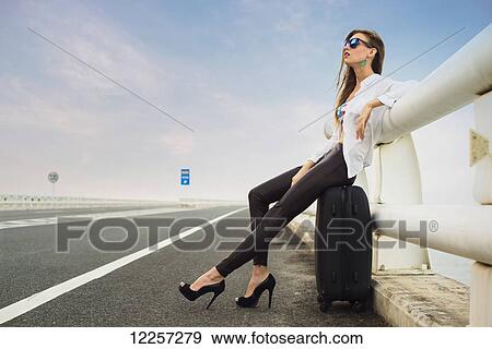 Woman hitchhiking on a highway, tired she sits in her luggage; Xiamen, Fujian, China View Large Photo Image Stock Photo - Woman hitchhiking on a highway, tired she sits in her luggage; Xiamen, Fujian, China. Fotosearch