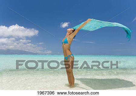 Stock Photograph - Woman Holding Turquoise Pareo Overhead, White Sand Beach.. Fotosearch
