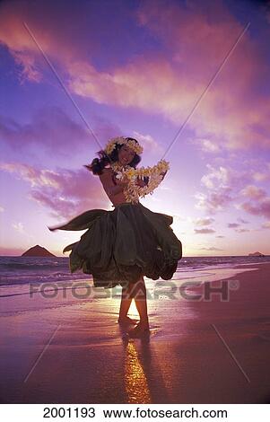 Stock Image - Woman Hula At Sunrise Wearing Ti-Leaf Skirt, Shoreline Pink Golden Sky Reflections Tropical Full Length View. Fotosearch