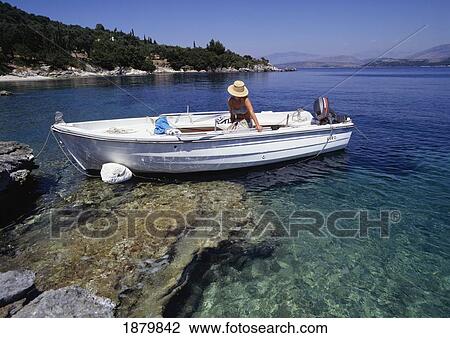 Stock Image - Woman In A Boat Near Coastline, Corfu. Fotosearch