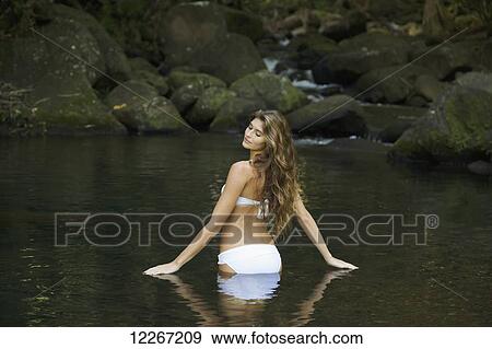Stock Photo - Woman in a white bikini standing in the water; Kauai, Hawaii, United States of America. Fotosearch
