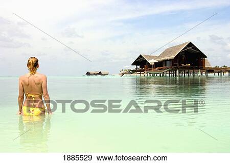 Stock Photo - Woman In Bikini Near Huts On Stilts. Fotosearch
