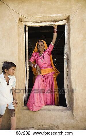 Stock Image - Woman In Colorful Sari Standing In Doorway Of House. Fotosearch