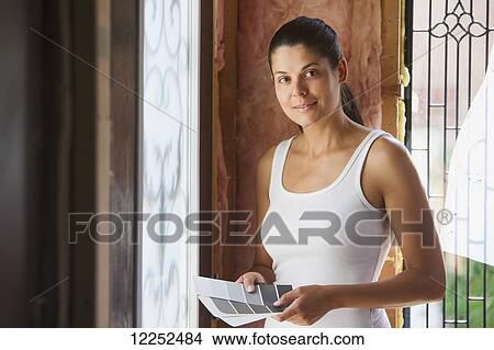 Picture - Woman in her 30s with color charts at entrance of her home that is being renovated; Bradford, Ontario, Canada. Fotosearch