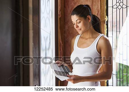 Stock Photography - Woman in her 30s with color charts at entrance of her home that is being renovated; Bradford, Ontario, Canada. Fotosearch