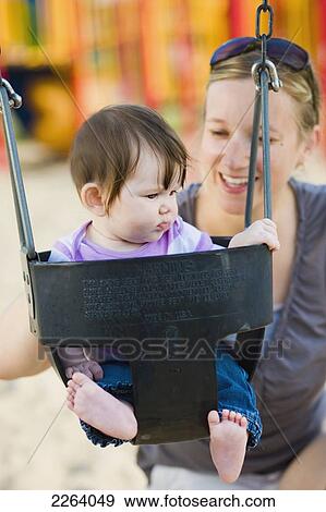 Woman In Her Late 20's In A Park With Her 6-Month-Old Daughter In A Swing; Ontario Canada View Large Photo Image Stock Photo - Woman In Her Late 20's In A Park With Her 6-Month-Old Daughter In A Swing; Ontario Canada. Fotosearch